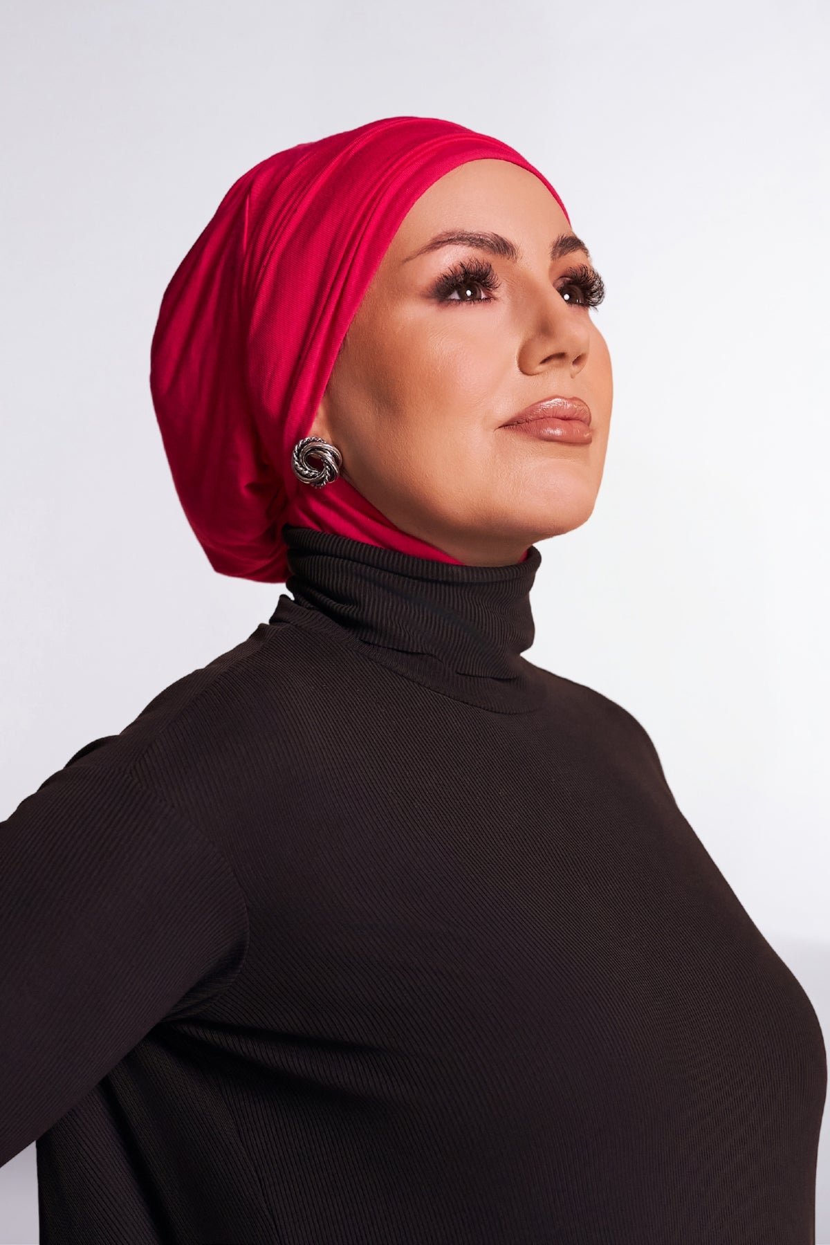 Hot Pink | Model wearing the Hot Pink DuoWear 2-in-1 Hijab styled as a turban, three-quarter view, paired with a black ribbed turtleneck.