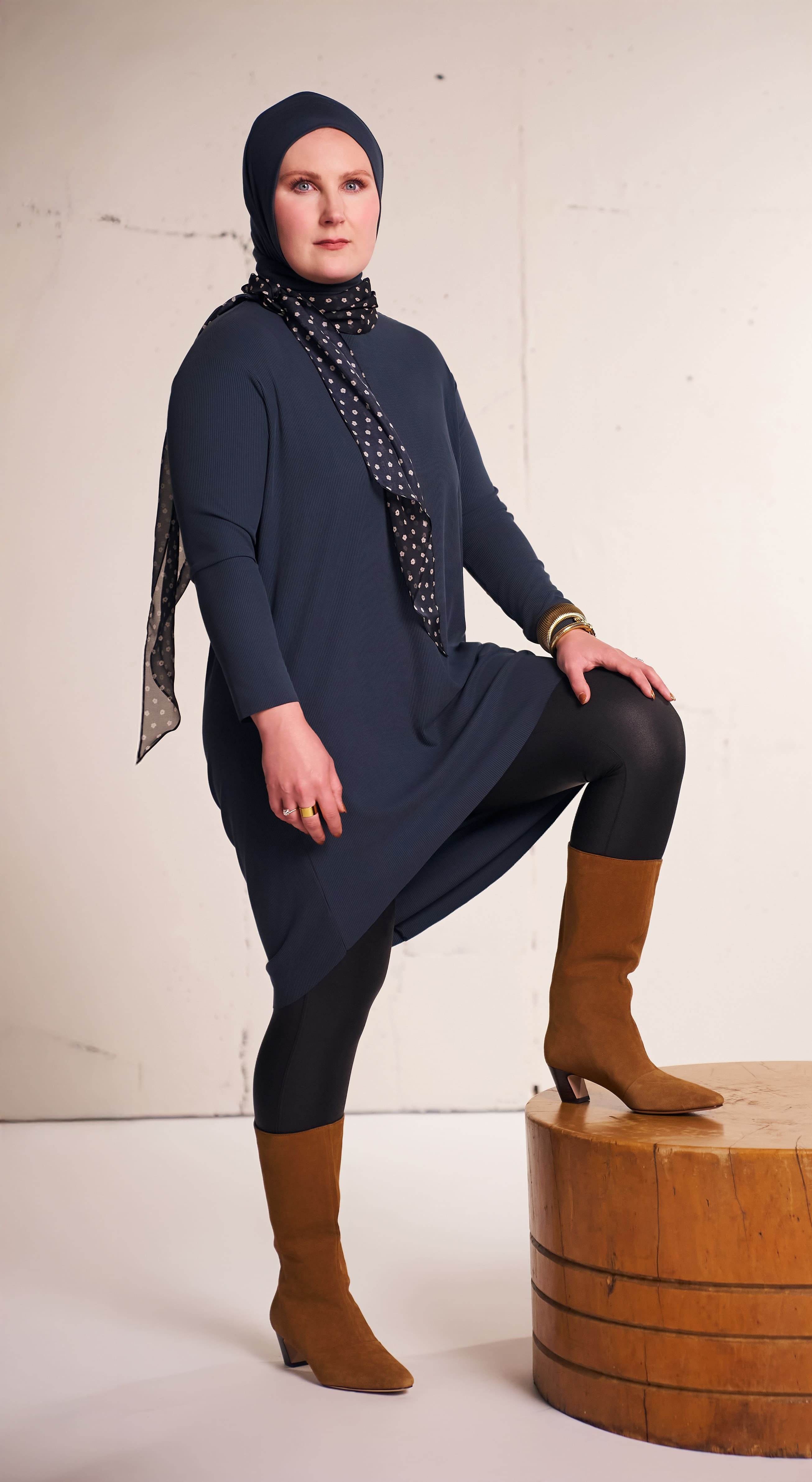 Woman standing in a studio wearing the Flow Tunic in charcoal with full-length coverage.