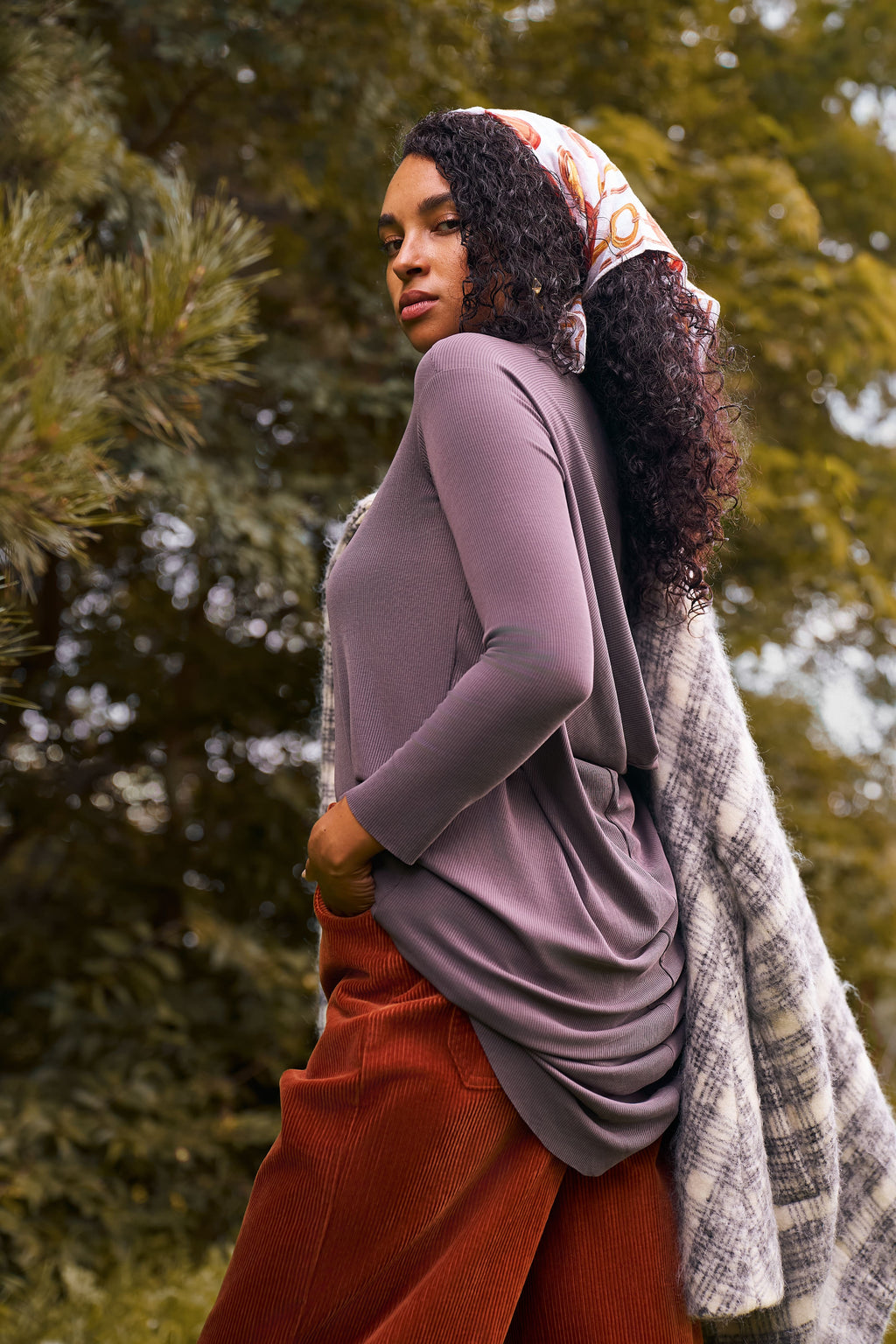 Outdoor image of a woman wearing the Flow Tunic in mink, shown from the side.