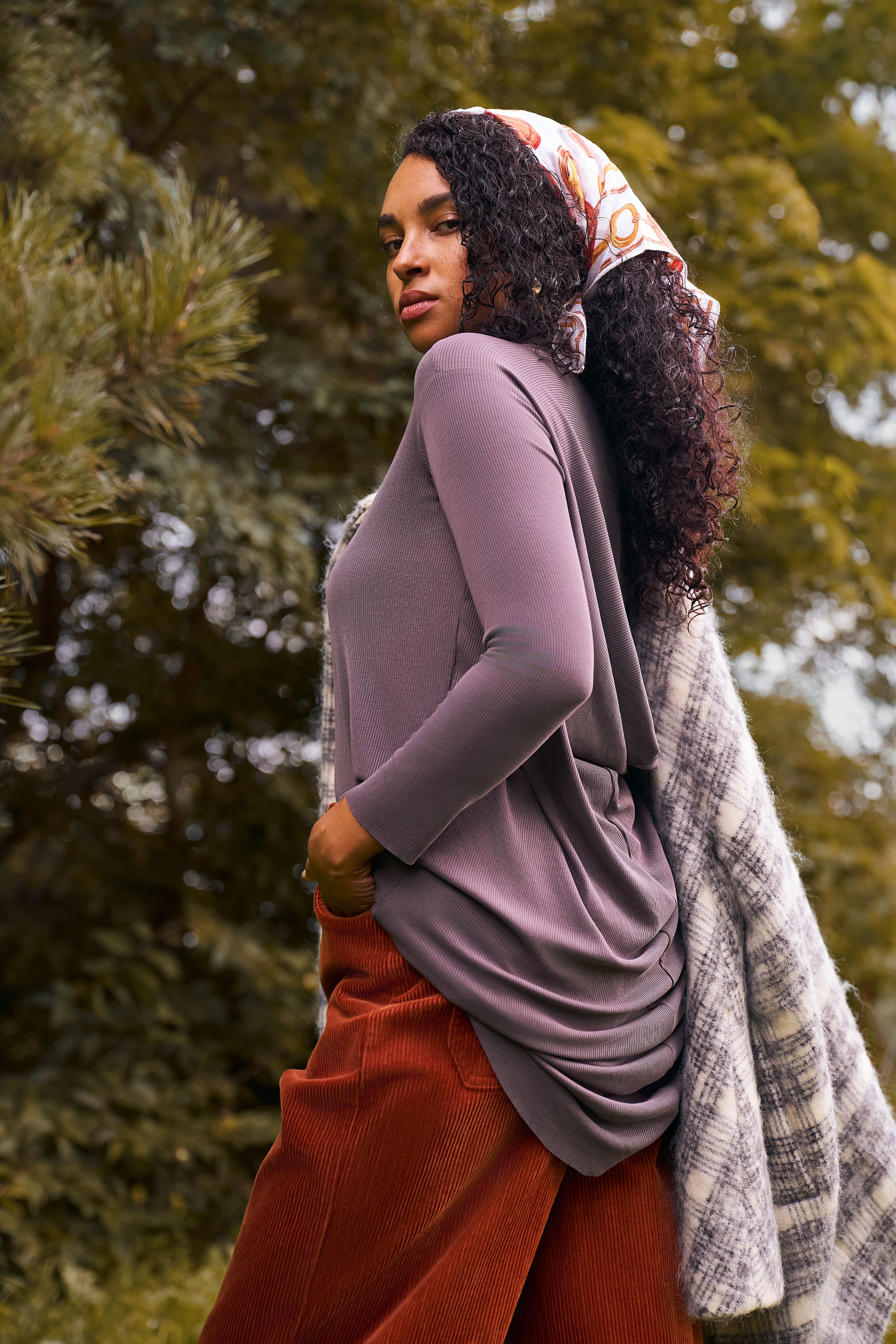 Outdoor image of a woman wearing the Flow Tunic in mink, shown from the side.