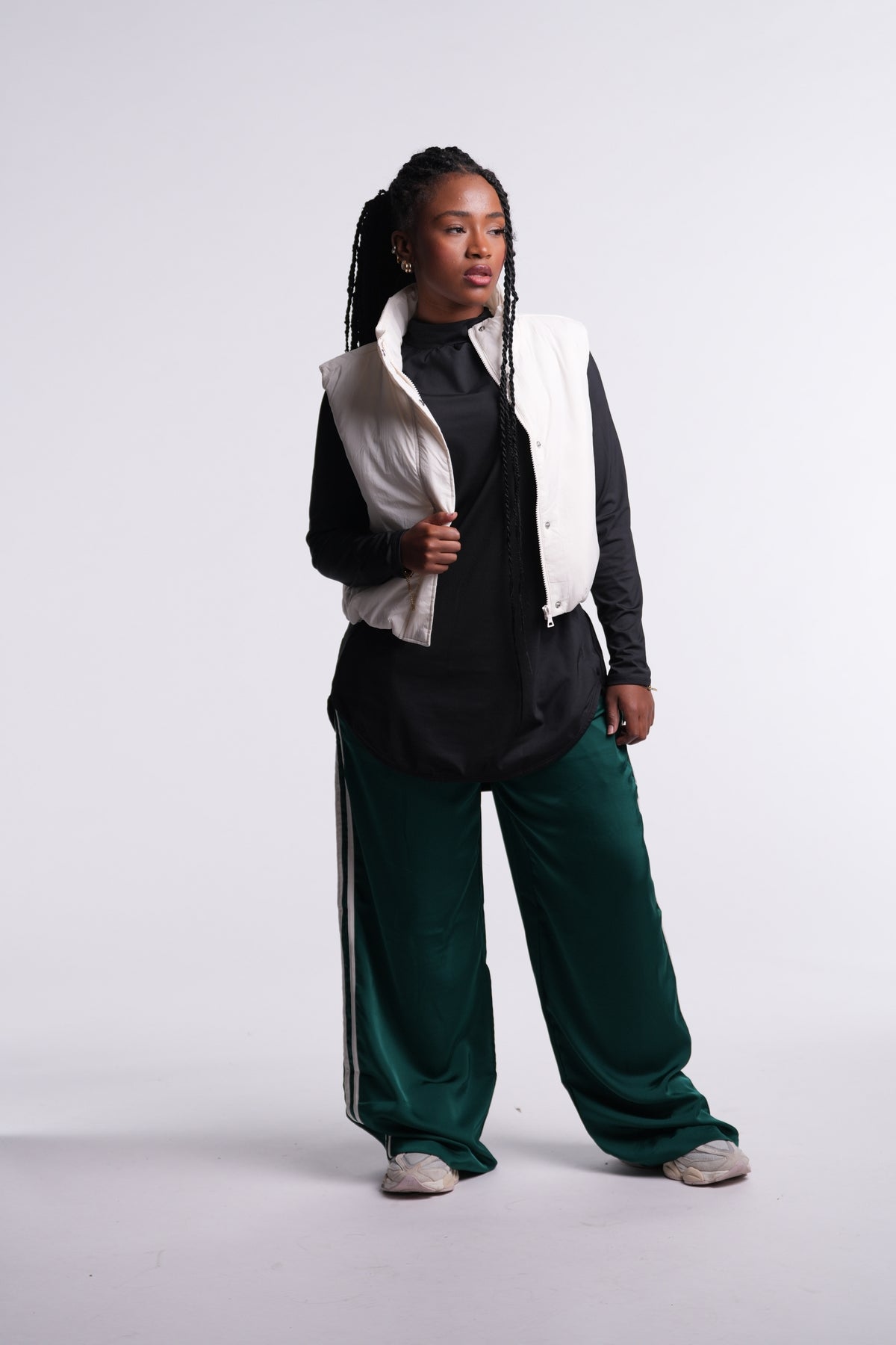 Black | Limitless Top layered under a cream puffer vest, worn with green track pants and sneakers