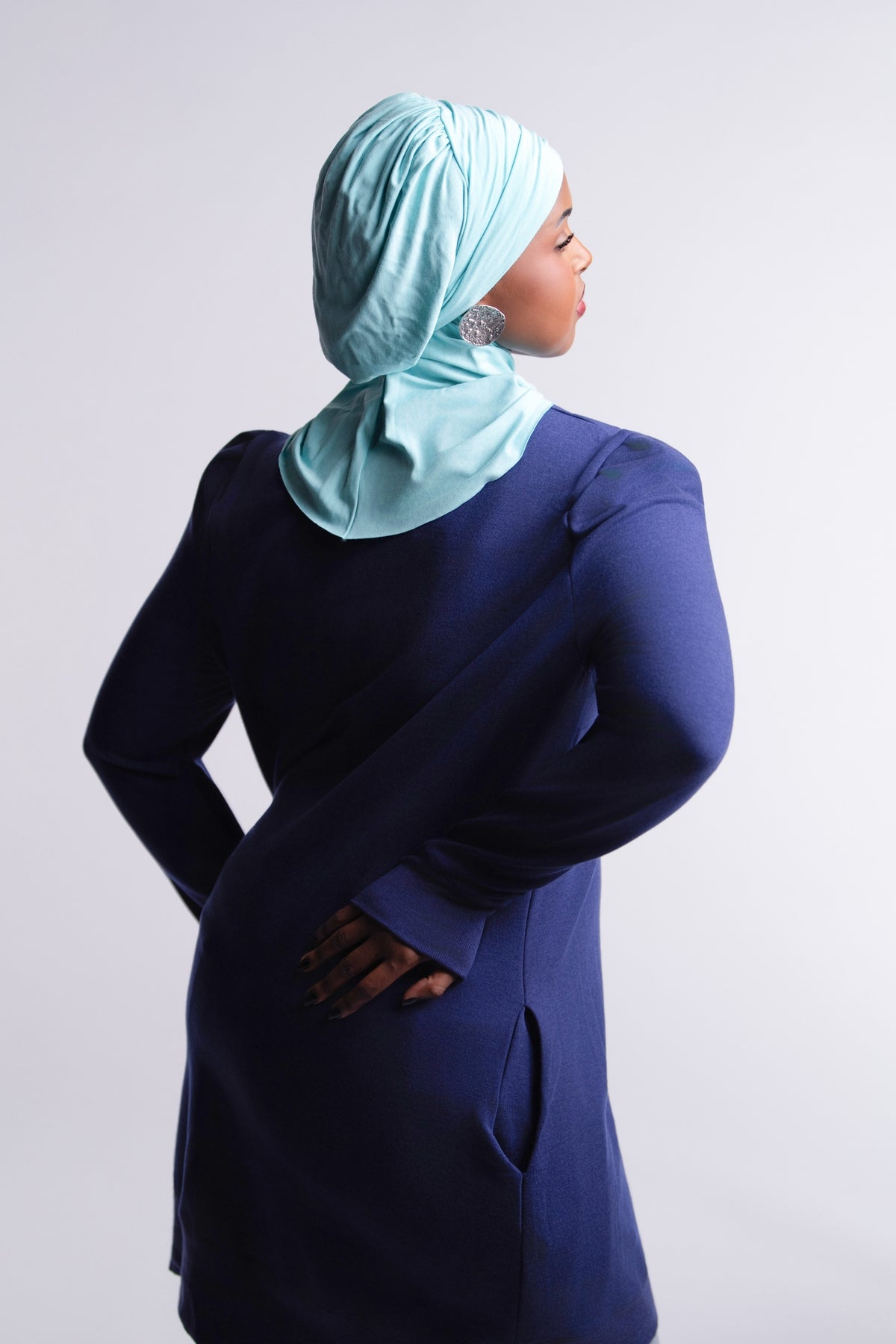 Revive Fleece Pullover back view, puff shoulders and split hem, worn with a turquoise hijab, light-wash jeans and sneakers