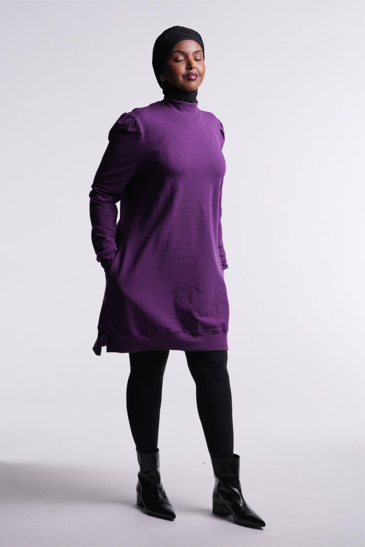 Berry Purple | Revive Fleece Pullover front view, mid-thigh length with puff shoulders, worn with black leggings and ankle boots