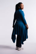 Teal | Back view of the Teal Convertible Veil Bodysuit with the overlay worn closed as a tunic, showing the flowing asymmetric hem, styled with dark jeans and white sneakers.
