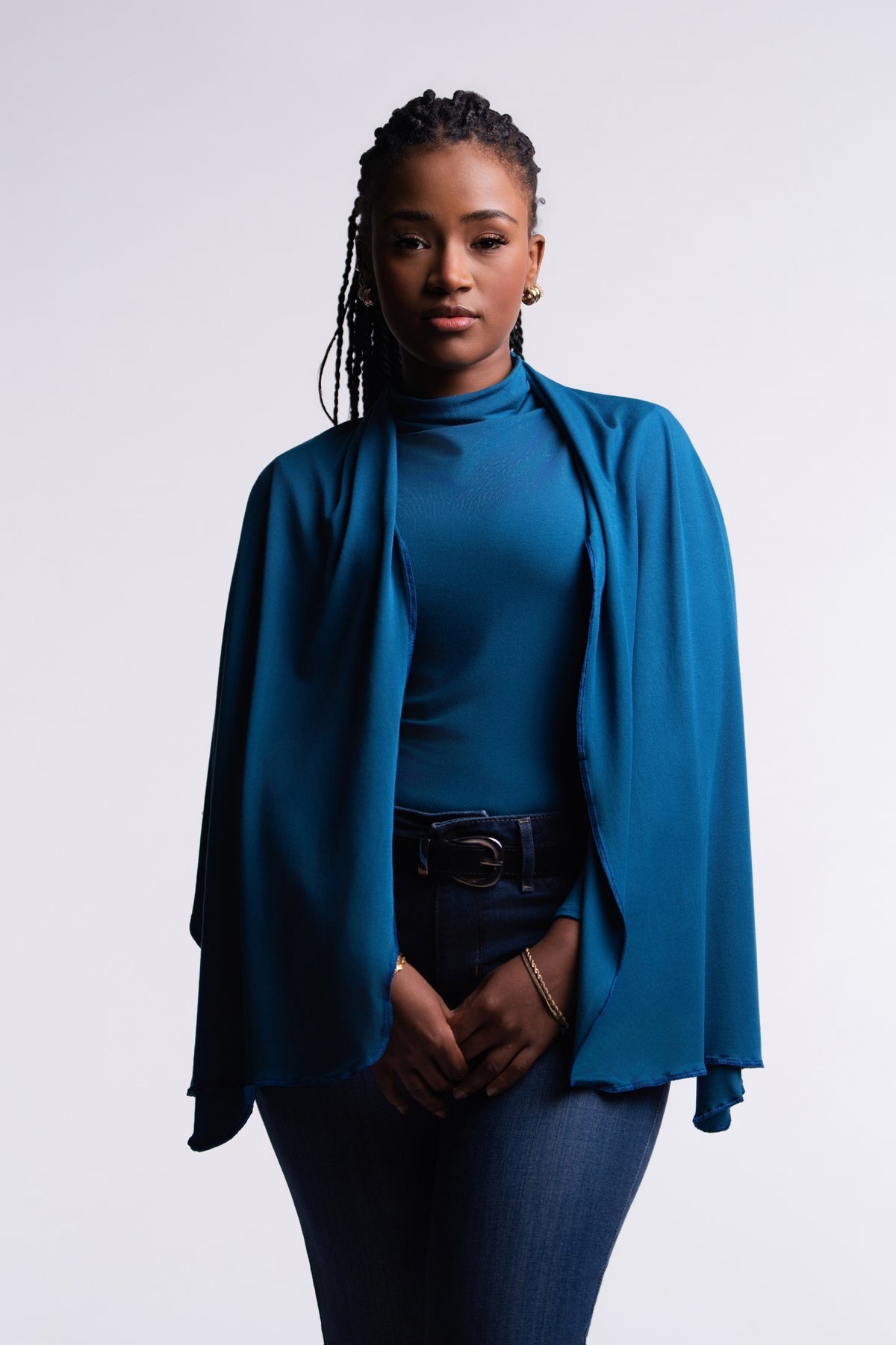 Teal | Front view of the Teal Convertible Veil Bodysuit with the overlay draped over the shoulders as a shawl, styled with dark jeans.