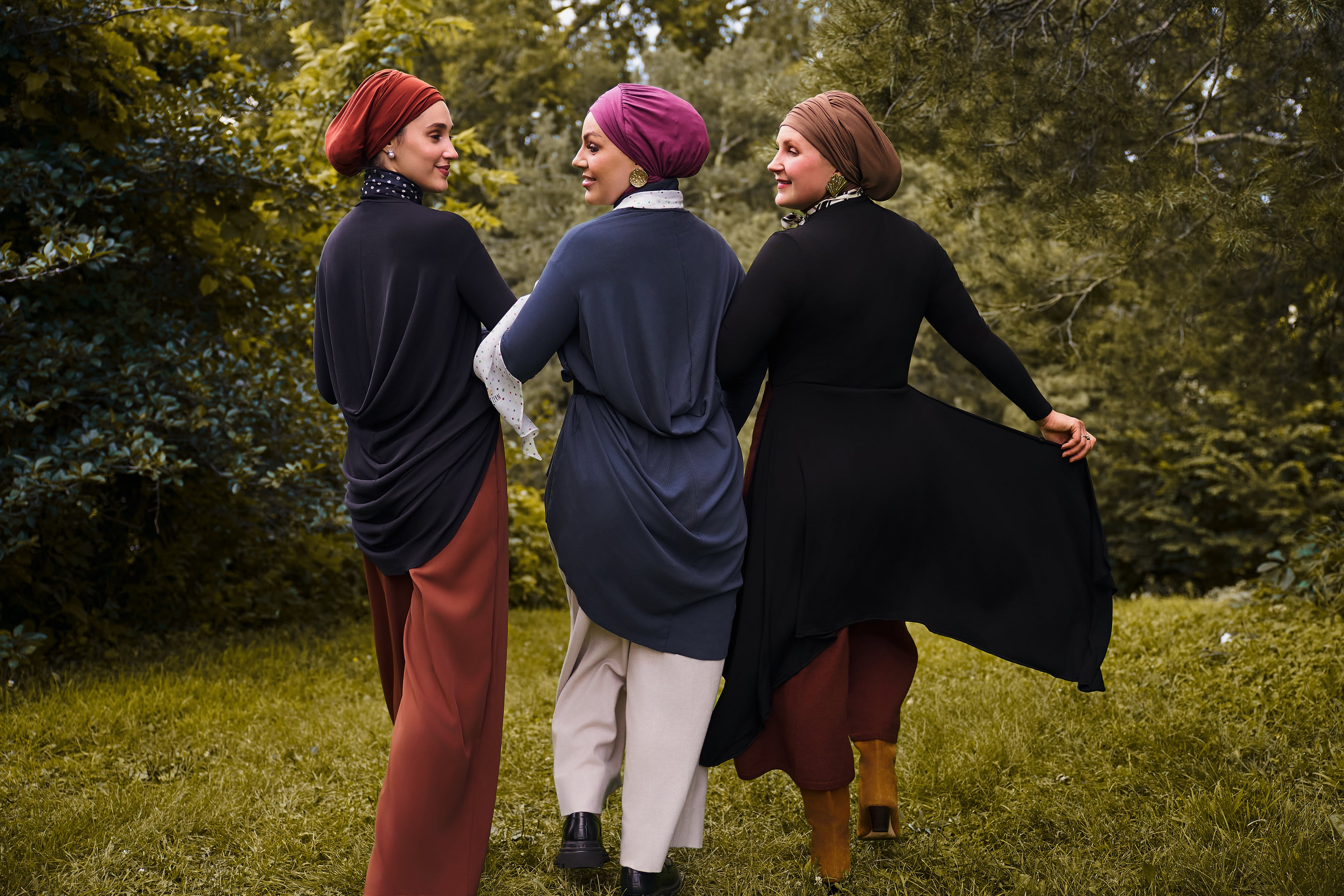 Three women sporting Yalla fits with one wearing the Veil Bodysuit in black with the overlay draped openly. 