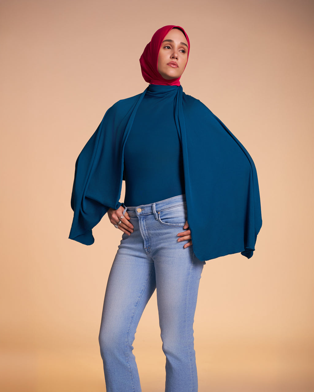 Woman wearing the Veil Bodysuit in teal with the overlay over her shoulders as a shawl. 